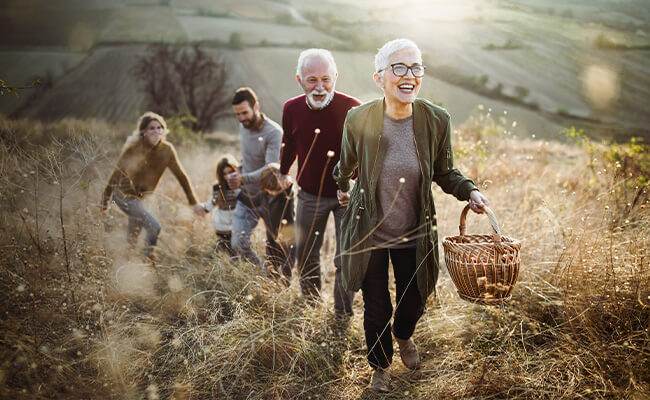 Una familia formada por dos ancianos, una madre, un padre y dos niños caminando juntos de la mano por la naturaleza